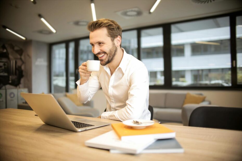 A man using laptop and drinking from a mug